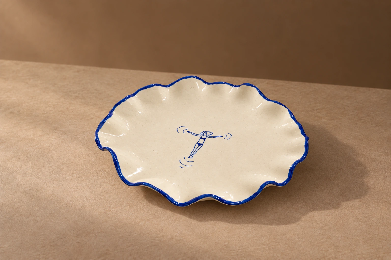Round cream platter with a scalloped cobalt-blue rim and a swimmer illustration